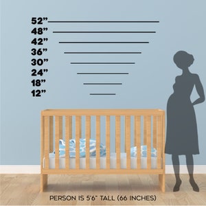 May include: A light wood baby crib with blue and white patterned pillows and a mattress. Black lines indicate heights from 12" to 52". A silhouette of a pregnant person stands to the right. Text reads: PERSON IS 5'6" TALL (66 INCHES).