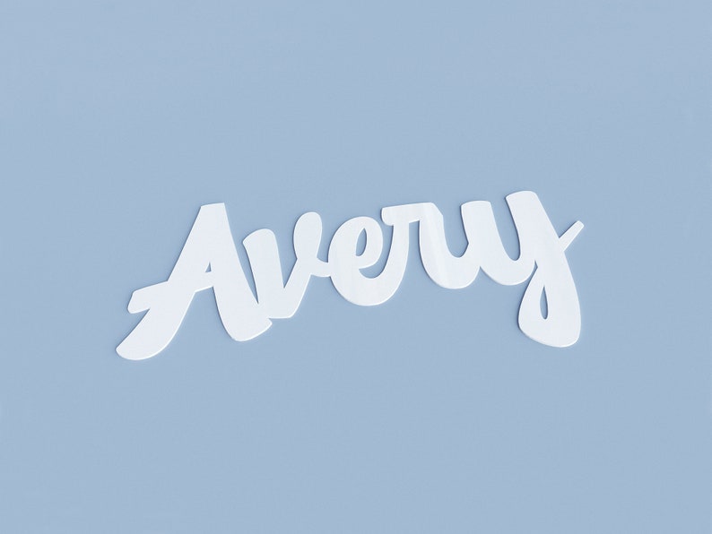 May include: The name Avery written in white cursive script on a light blue background.