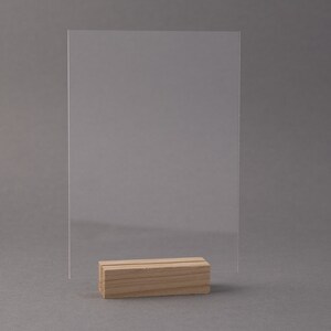 May include: A clear acrylic sign holder with a wooden base. The sign holder is empty and ready to display a message.