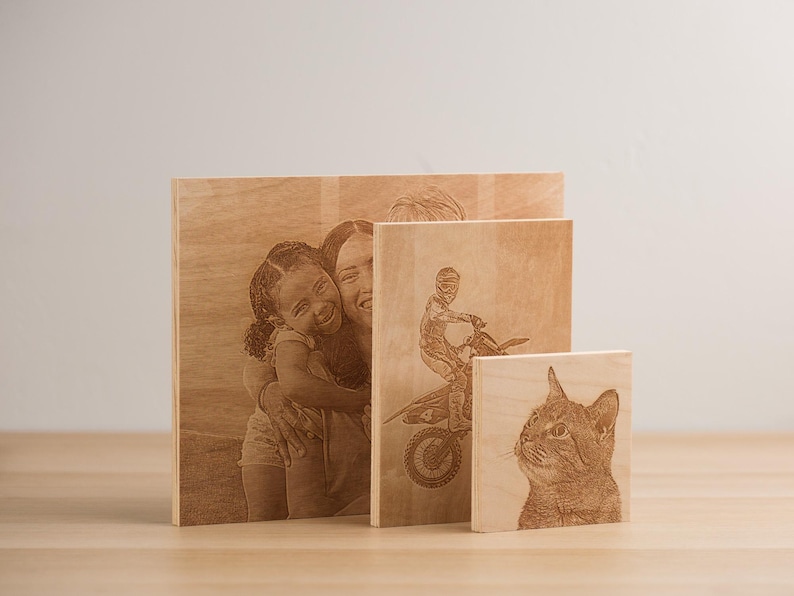 May include: Three wooden plaques with laser-engraved images. The largest plaque features a woman and a girl hugging. The middle plaque shows a person riding a dirt bike. The smallest plaque shows a cat's head.