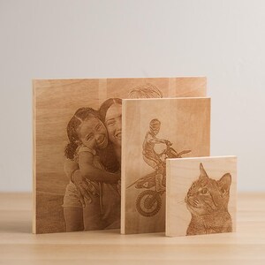 May include: Three wooden plaques with laser-engraved images. The largest plaque features a woman and a girl hugging. The middle plaque shows a person riding a dirt bike. The smallest plaque shows a cat's head.