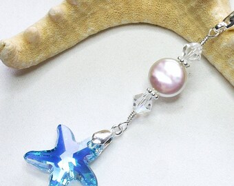 May include: A silver charm with a light blue starfish, a pink pearl, and clear crystal beads. The charm is attached to a silver lobster clasp.