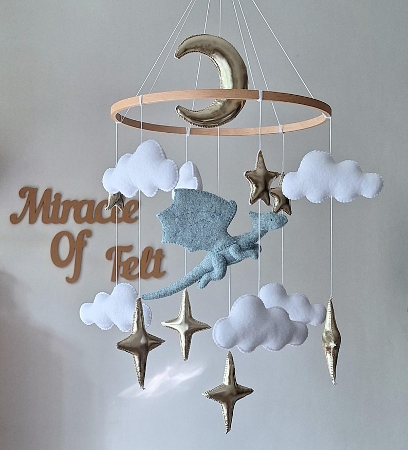 Móvil de bebé con dragón volador de fieltro, estrellas doradas y luna. Decoración colgante de fantasía para habitación infantil. imagen 1