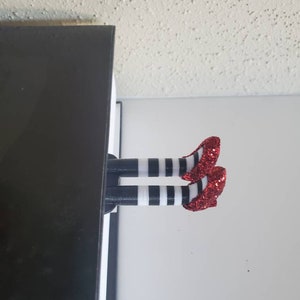 May include: A red and white striped bookmark with red glitter shoes. The bookmark is shaped like a pair of legs sticking out of a book.