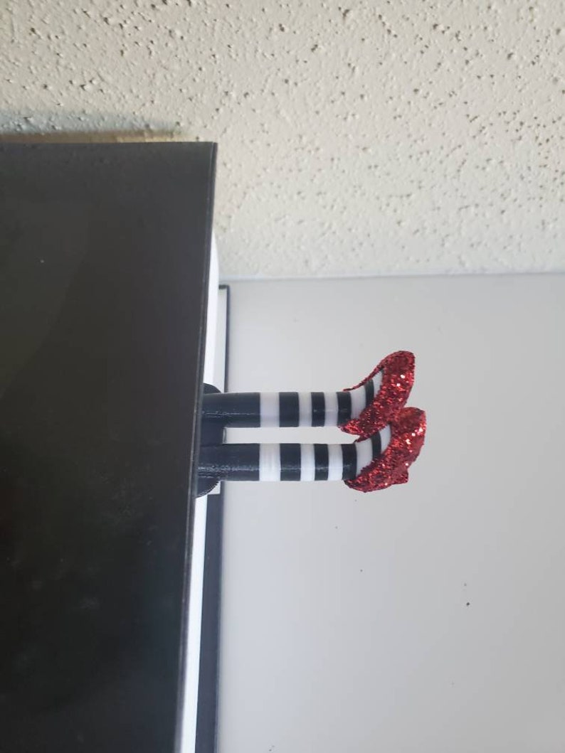 May include: A red and white striped bookmark with red glitter shoes. The bookmark is shaped like a pair of legs sticking out of a book.