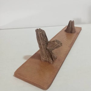 May include: A wooden stand with two tree trunk-shaped holders. The stand is brown and has a smooth surface.