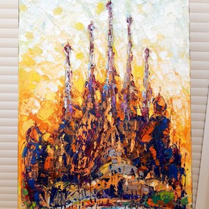 May include: A colourful, abstract painting of a famous cathedral with multiple spires. The painting is done in a thick, impasto style with visible brushstrokes. The colours are mostly warm, with shades of yellow, orange, brown, and purple.