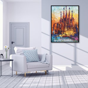 May include: A painting depicting a colourful cityscape with a large building at its centre. The building has numerous towers and is painted in shades of orange, yellow, and brown. The sky is a bright blue with clouds. The painting is framed in black.