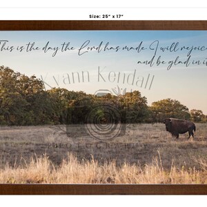May include: Framed landscape print showing a bison in a field with trees under a blue sky. The print includes the text "This is the day the Lord has made. I will rejoice and be glad in it." The frame measures 63.5 x 43.2 cm.