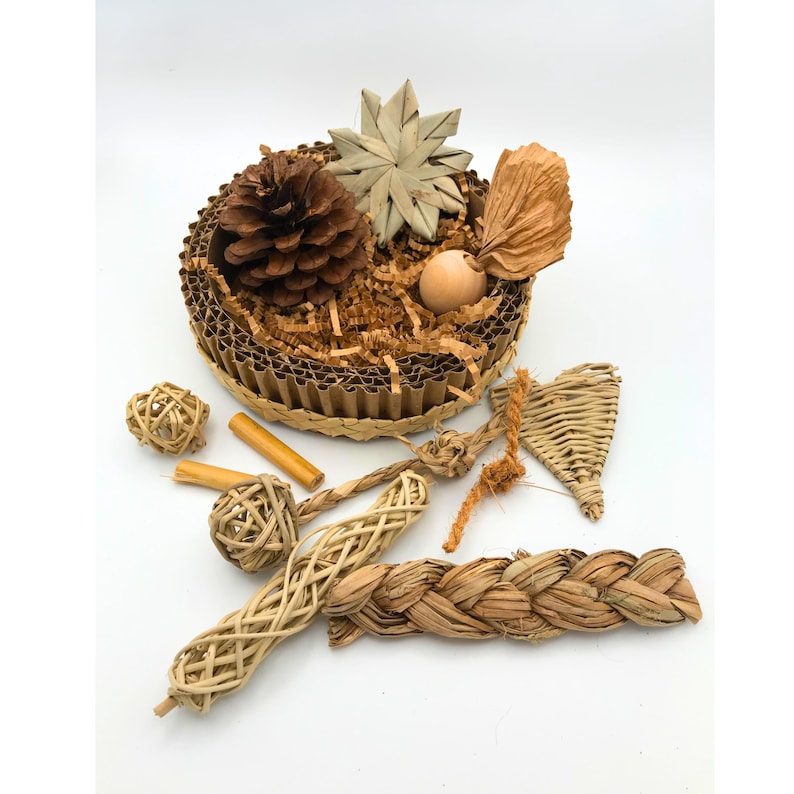 May include: A selection of natural pet toys, featuring a cardboard nest with shredded paper, a pine cone, and various woven and wooden items. The toys are in shades of brown and beige.