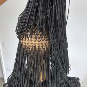 May include: A black wig with long, thin braids. The braids are all the same length and are tied together at the top of the head.
