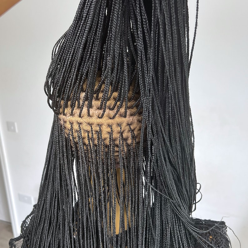May include: A black wig with long, thin braids. The braids are all the same length and are tied together at the top of the head.