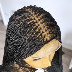 May include: Black braided wig with a lace front. The wig is styled in small, thin braids.