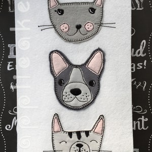 May include: Three felt animal faces, a gray cat, a gray and black French bulldog, and a gray tabby cat, are sewn onto a white background.