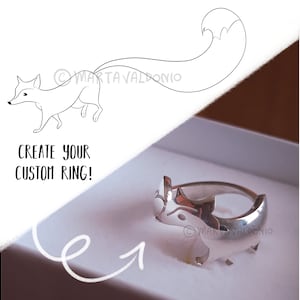 May include: A silver ring with a fox design. The ring is in a white box with the text "Create your custom ring!" on the side.
