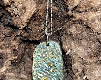 May include: A silver chain necklace with a pendant made of iridescent abalone shell. The pendant is a freeform shape with a textured surface.