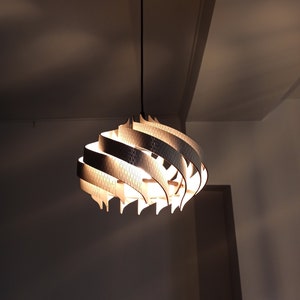 Peut inclure: Un luminaire suspendu en bois moderne avec un design en spirale. La lumière est allumée et diffuse une lueur chaude.