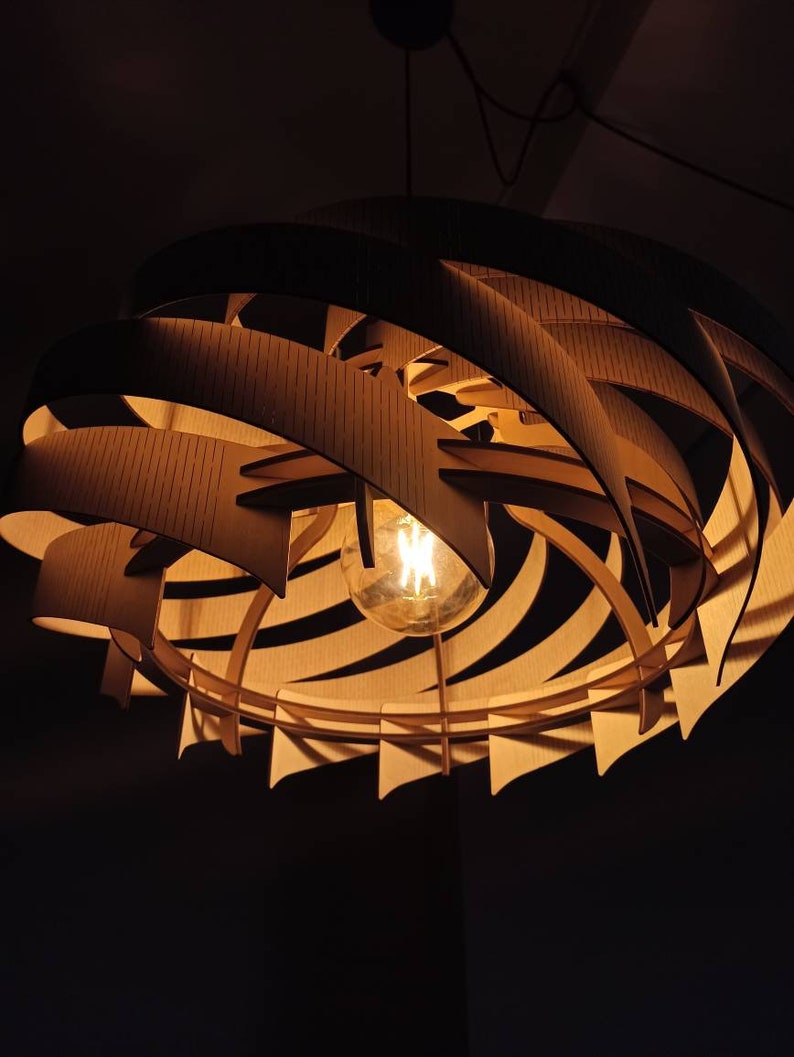 May include: A wooden pendant light fixture with a spiral design and a warm white light bulb. The light fixture is made of multiple layers of wood that are stacked on top of each other to create a spiral shape.