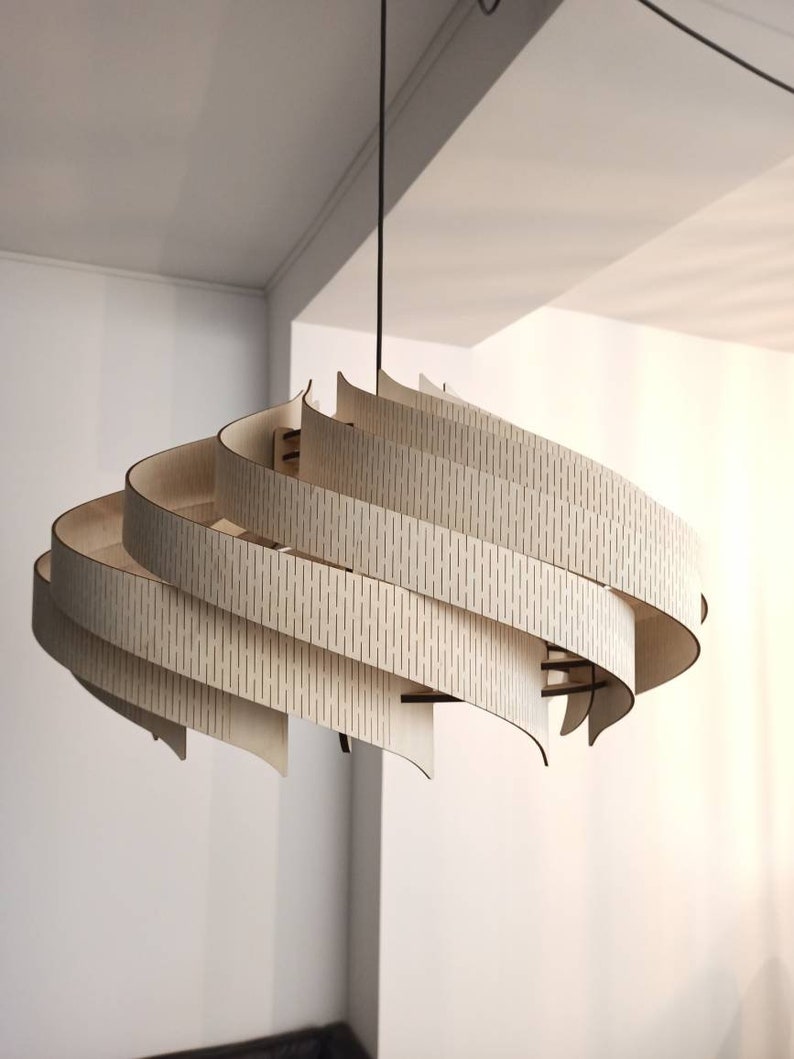 May include: A modern, wooden pendant light fixture with a unique, swirling design. The light is made of multiple layers of thin, light wood, creating a layered effect. The wood has a natural, light brown color.