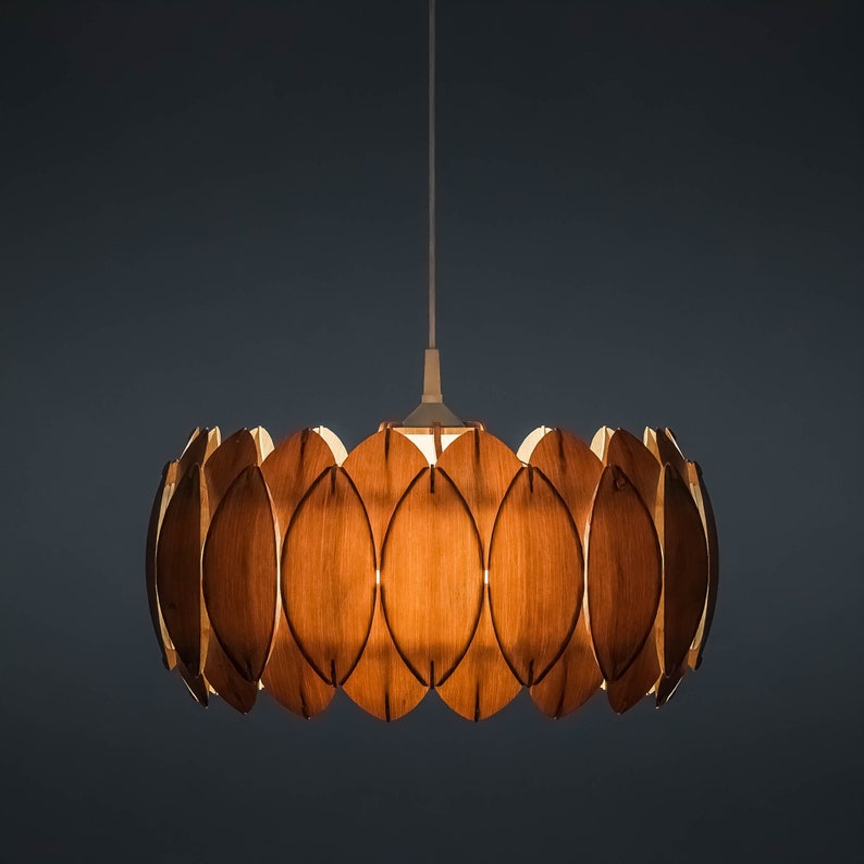 May include: A wooden pendant light fixture with a circular design. The fixture is made up of multiple overlapping wooden leaves, creating a unique and modern look.
