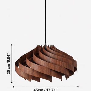 May include: A wooden pendant light fixture with a spiral design. The fixture is brown and measures 9.84 inches in height and 17.71 inches in diameter. It hangs from a black cord and a black ceiling mount.