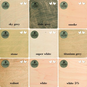 May include: A selection of wooden squares in shades like silver grey, sky grey, and slate grey, each with a colour name and a logo featuring butterflies. The colour range includes 'smoke' and 'winter blush'. Measurements are not applicable.