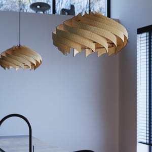 May include: Two pendant lights featuring spiraling, light-colored wooden slats arranged in a circular, layered pattern. Each fixture is suspended by a thin black cord from the ceiling, creating a structured, rhythmic design with visible grain.