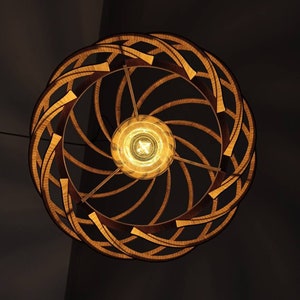 Może przedstawiać: Drewniana lampa sufitowa o spiralnym wzorze z ciepłą żar&oacute;wką. Lampa wykonana jest z naturalnego drewna i ma rustykalny wygląd.