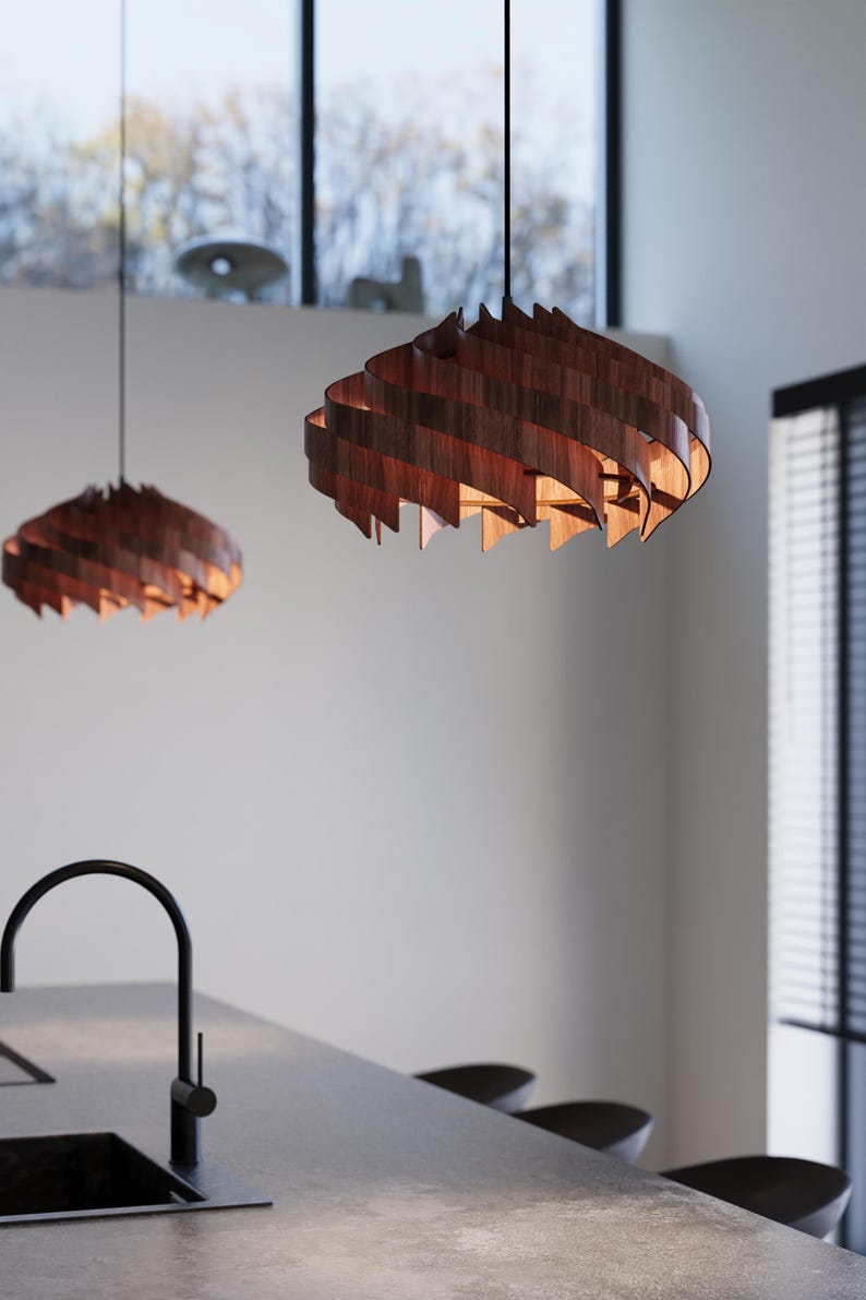 May include: Two wooden pendant lights with a spiral design hang from the ceiling. The lamps are made of dark brown wood and emit a warm, inviting glow. The lights are suspended above a kitchen island.
