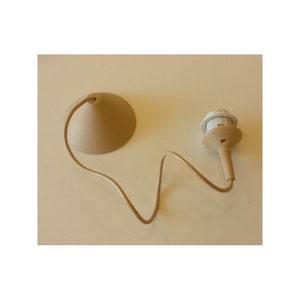 May include: A beige ceiling light fitting, featuring a conical canopy and a bulb socket, connected by a beige wire. This light fitting is designed for overhead illumination.
