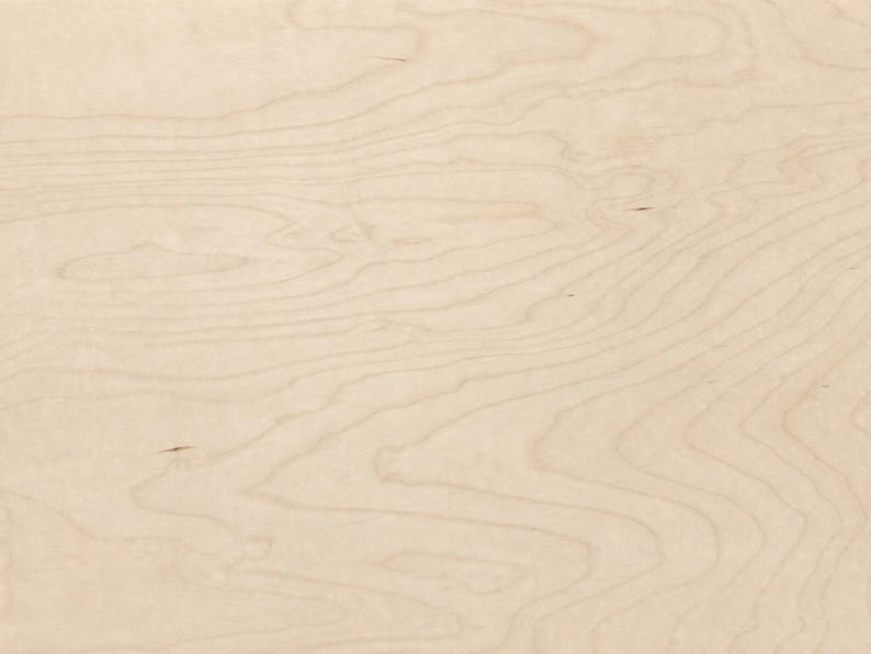 May include: A light beige wooden surface featuring a natural grain pattern with flowing, organic lines in slightly darker tan tones. The texture is smooth and uniform, showcasing the characteristic swirls and rings of light-colored wood.