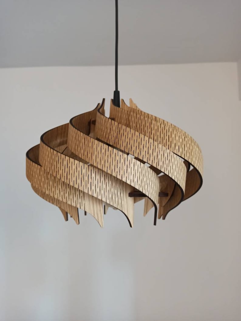 May include: A modern, wooden pendant light fixture with a swirling, layered design. The light is made of multiple pieces of wood that are stacked and curved to create a unique and eye-catching shape.