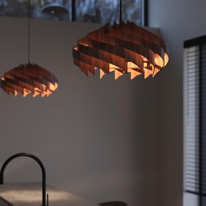May include: Two wooden pendant lights with a spiral design hang from the ceiling. The lights are made of thin, curved wooden slats that create a layered effect. The warm light from the bulbs inside illuminates the wood, creating a cozy atmosphere.