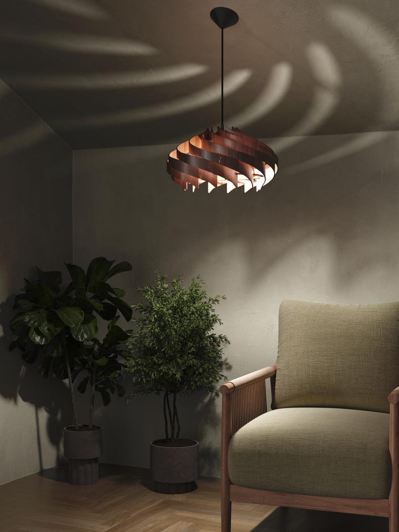May include: A wooden pendant light fixture with a spiral design hangs from the ceiling. The light fixture is brown and casts a warm glow. The room also features a green armchair, potted plants, and a neutral-toned wall.