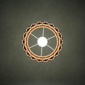 May include: A round, wooden ceiling light fixture with a geometric design. The light is on and emits a warm, white glow.