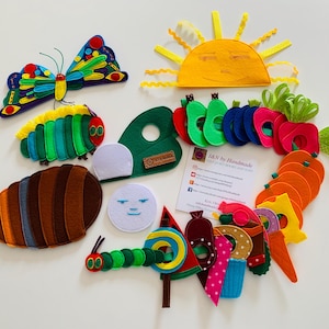 May include: Felt craft set featuring characters from the children's book The Very Hungry Caterpillar. The set includes a green caterpillar, a brown cocoon, a butterfly with colourful wings, a sun, a watermelon, a lollipop, a piece of cake, a pickle, a strawberry, an apple, a pear, an orange, a plum, a cheese wedge, and a carrot. The set is perfect for imaginative play and storytelling.