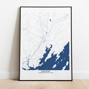 May include: A black framed print of a map of Freeport, Maine. The map shows the town's roads, waterways, and surrounding area. The text "Freeport, Cumberland County, Maine" is printed at the bottom of the map.