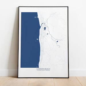 May include: A framed map of Cannon Beach, Clatsop County, Oregon. The map is printed in blue and white on a white background. The map shows the coastline, roads, and other features of the area.
