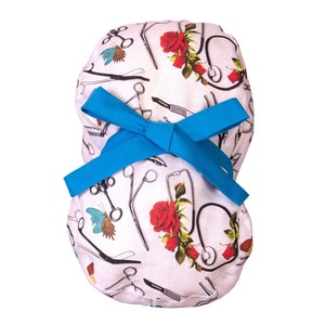 Può includere: Cappello chirurgico bianco con fiocco blu. Il cappello è decorato con strumenti medici, rose rosse e farfalle. Il fiocco è di un blu brillante e uniforme. Il cappello è progettato per essere indossato in un ambiente medico.