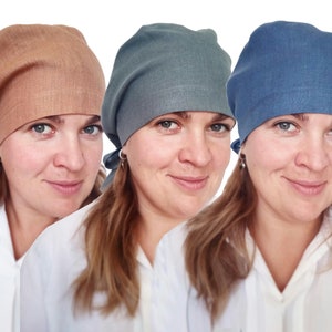 May include: Three women wearing different coloured linen headbands. The headbands are tied at the back of the head. The women are wearing white shirts.