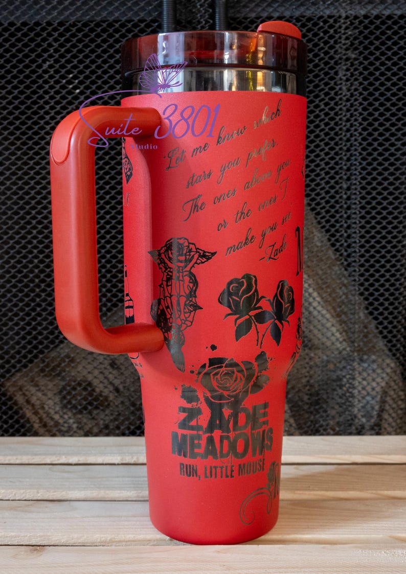 May include: Red stainless steel tumbler with a black handle and a black design featuring roses, a butterfly, and the text "Let me know which stars you prefer. The ones above you or the ones I make you see." -Zade. The tumbler also features the text "Zade Meadows" and "Run, Little Mouse".