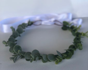 May include: A green eucalyptus leaf wreath with a white ribbon tied around it.
