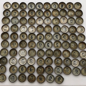 May include: A collection of 100 bottle caps featuring different images of people. The bottle caps are arranged in a grid pattern on a white surface.