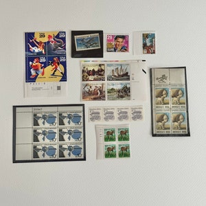 May include: A collection of vintage postage stamps featuring various themes, including Elvis Presley, a circus, a plane, a ship, a deer, and a sheep. The stamps are arranged in rows and columns on a white background.