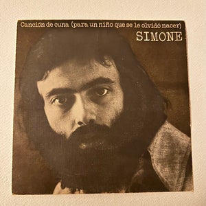 May include: A black and white photo of a man with a beard. The text "Cancion de cuna (para un niño que se le olvidó nacer)" and "SIMONE" are printed on the image.