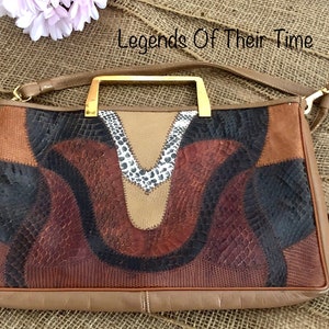 May include: A brown leather handbag with a gold handle and a patchwork design featuring different textures and colours. The bag has a long strap and is made of genuine leather.