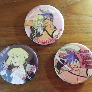 May include: Three round button pins featuring anime characters with colorful backgrounds and text. The first pin features two characters with the text "GALOLIO FIGARO MAGNIFICO". The second pin features a character with the text "TO BURN Es To BE FREE". The third pin features a character with the text "I'LL PUT You OUT WITH MY BURNING SOUL!"