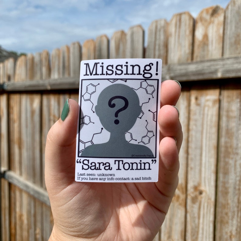 Puede incluir: Una pegatina blanca con texto negro que dice "Missing!" y presenta una silueta de una persona con un signo de interrogaci&oacute;n sobre su cabeza. El texto debajo de la silueta dice "Sara Tonin" e incluye informaci&oacute;n de contacto.