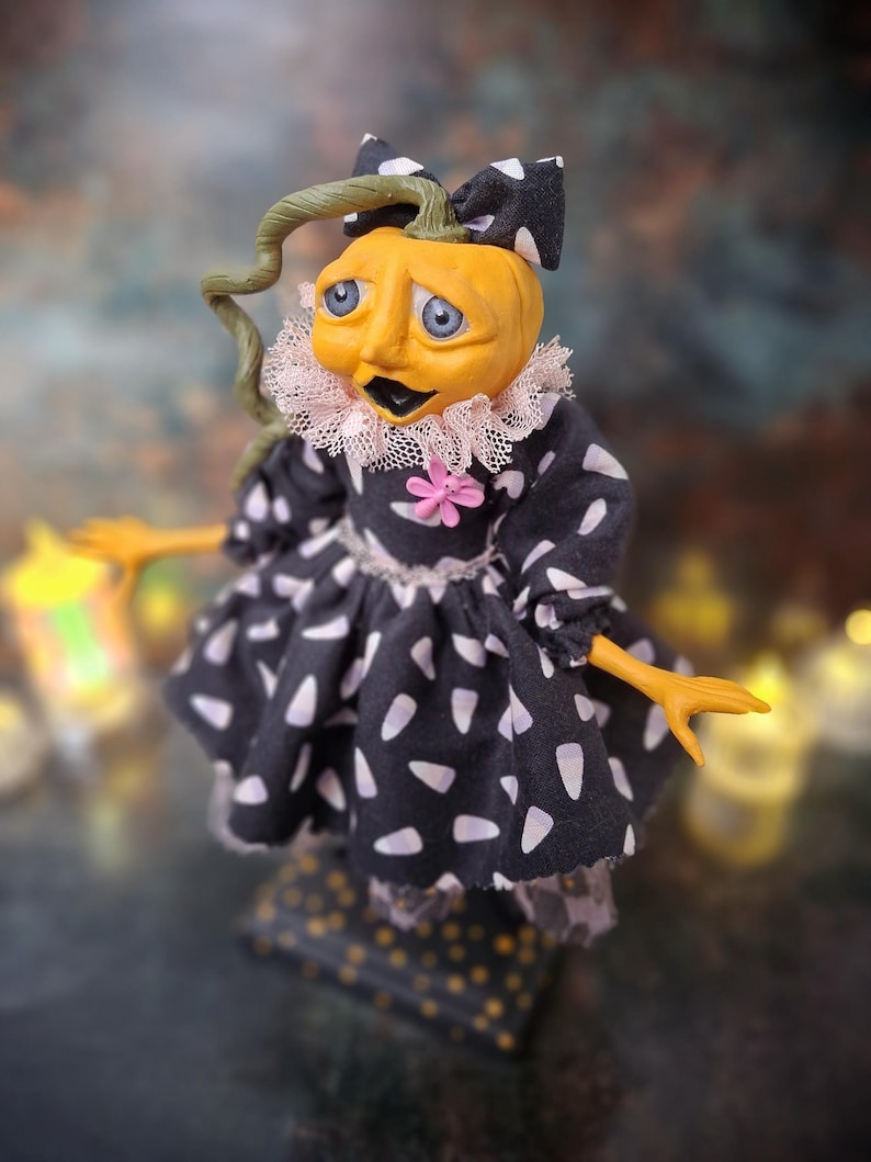 Close-up left side view of the handmade spooky Halloween pumpkin art doll, highlighting her hand-painted face, pumpkin-inspired outfit, and festive Halloween accents.