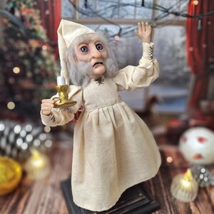 A right-angled view of the Ebenezer Scrooge Art Doll looking upward, showcasing his hand-painted facial expression and detailed vintage-inspired outfit. The doll’s mixed-media textures and subtle holiday accents are highlighted, capturing the whimsical yet classic charm of the character.